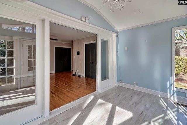 spare room featuring light hardwood / wood-style floors, an inviting chandelier, ornamental molding, and vaulted ceiling