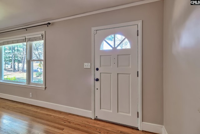 foyer entrance with crown molding and light hardwood / wood-style floors