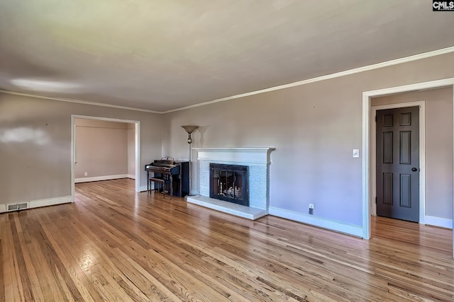 unfurnished living room featuring crown molding, light hardwood / wood-style flooring, and a brick fireplace