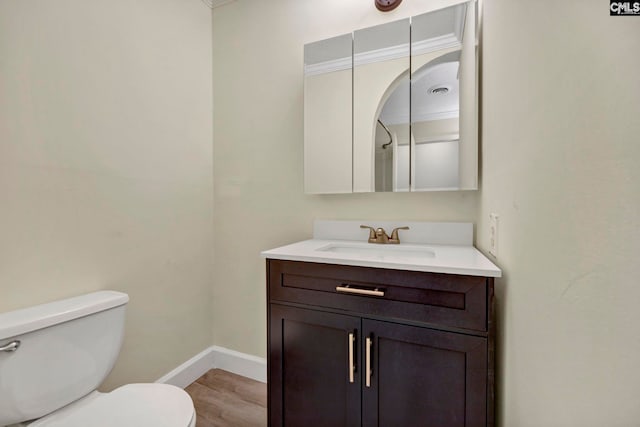 bathroom with wood-type flooring, vanity, toilet, and crown molding