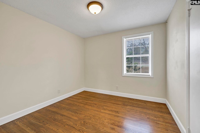 spare room with a textured ceiling and dark hardwood / wood-style flooring