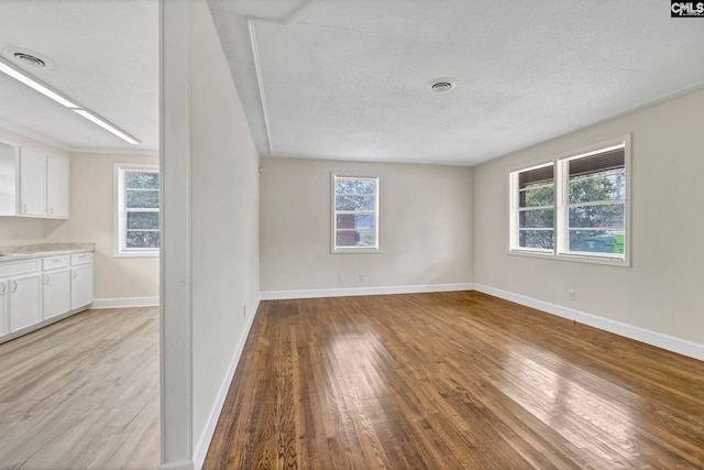 empty room featuring a textured ceiling and light hardwood / wood-style floors