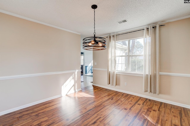 unfurnished dining area featuring a notable chandelier, crown molding, wood-type flooring, and a textured ceiling