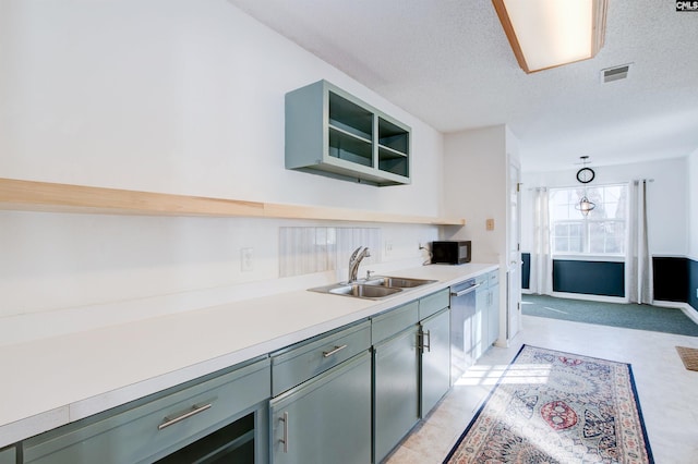 kitchen featuring dishwasher, sink, decorative light fixtures, and a textured ceiling