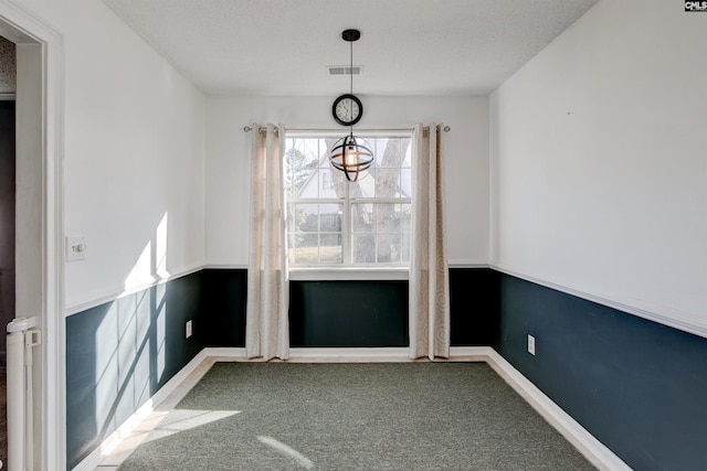 unfurnished dining area with a textured ceiling and carpet floors