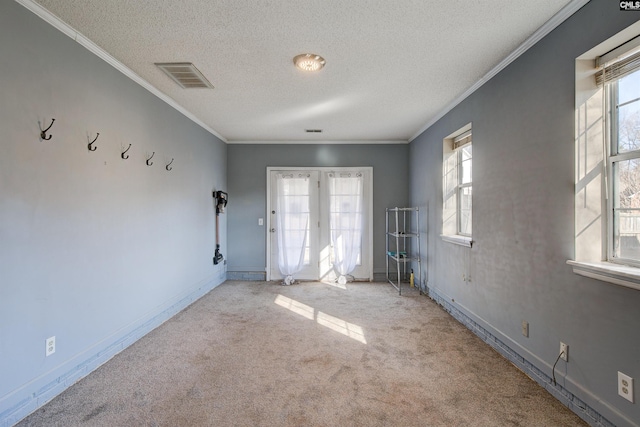 carpeted spare room featuring ornamental molding, a textured ceiling, and french doors