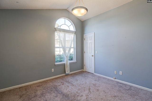 carpeted spare room with vaulted ceiling