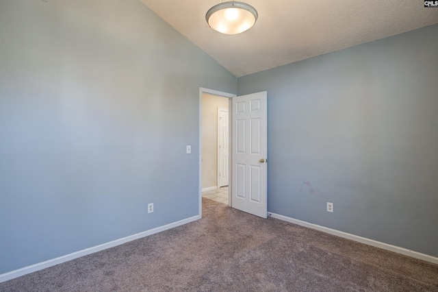 carpeted empty room with vaulted ceiling