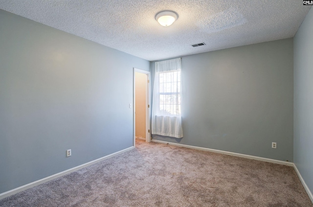 spare room featuring a textured ceiling and light carpet