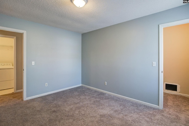 carpeted spare room with washer / dryer and a textured ceiling