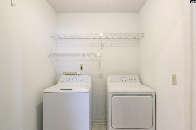 laundry room with a textured ceiling and washer and clothes dryer