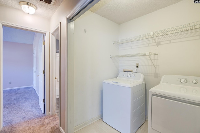 washroom with washer and clothes dryer, light carpet, and a textured ceiling