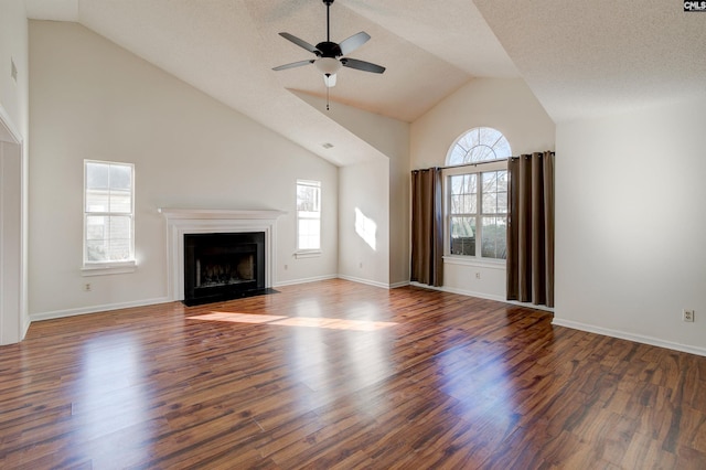 unfurnished living room with a textured ceiling, ceiling fan, dark wood-type flooring, and vaulted ceiling