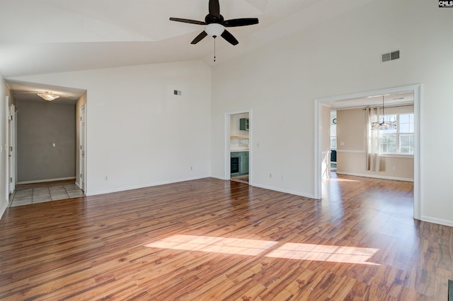 unfurnished living room featuring hardwood / wood-style floors, ceiling fan with notable chandelier, and high vaulted ceiling