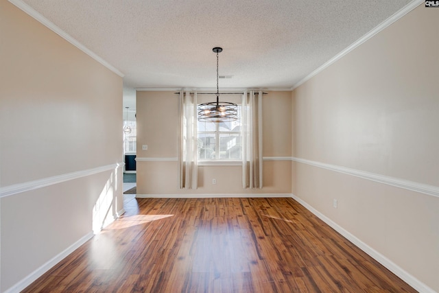 unfurnished dining area featuring ornamental molding, wood-type flooring, a textured ceiling, and a chandelier