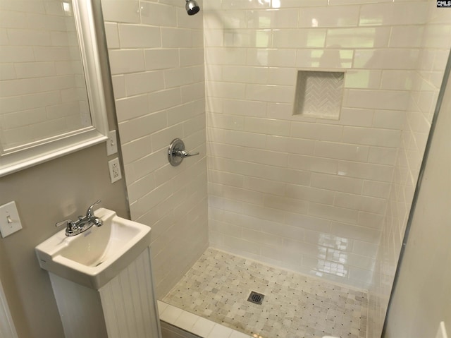 bathroom with tiled shower and sink