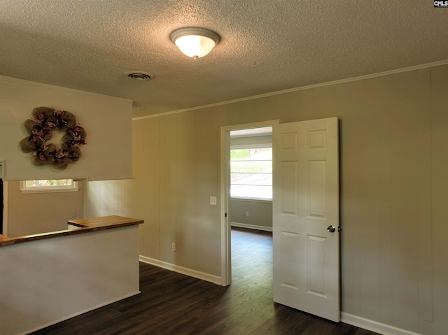 spare room with a textured ceiling, ornamental molding, and dark wood-type flooring