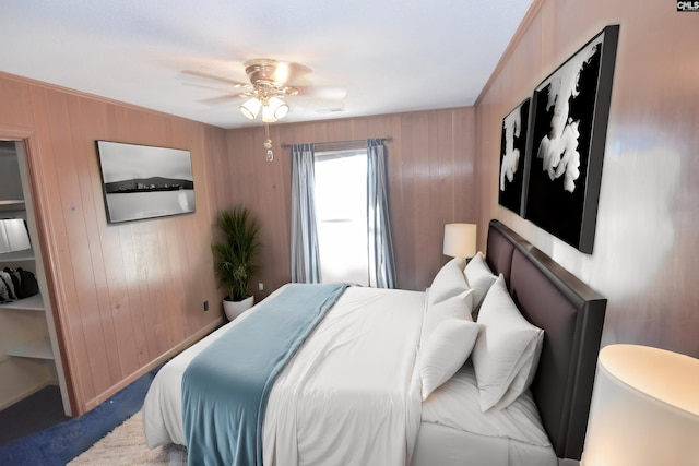 bedroom with carpet, ceiling fan, and wooden walls