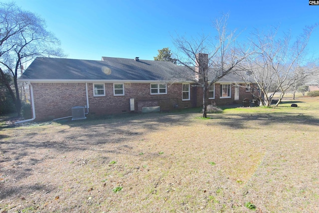 rear view of house with central AC and a yard