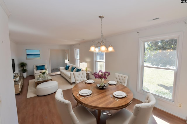 dining room featuring a wealth of natural light, crown molding, wood-type flooring, and an inviting chandelier