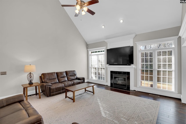 living room with a tiled fireplace, ceiling fan, dark hardwood / wood-style flooring, and high vaulted ceiling