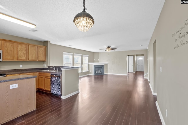 kitchen featuring dishwashing machine, pendant lighting, dark hardwood / wood-style flooring, and ceiling fan with notable chandelier