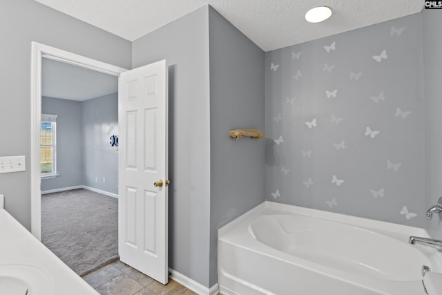 bathroom featuring tile patterned floors, a tub to relax in, and a textured ceiling