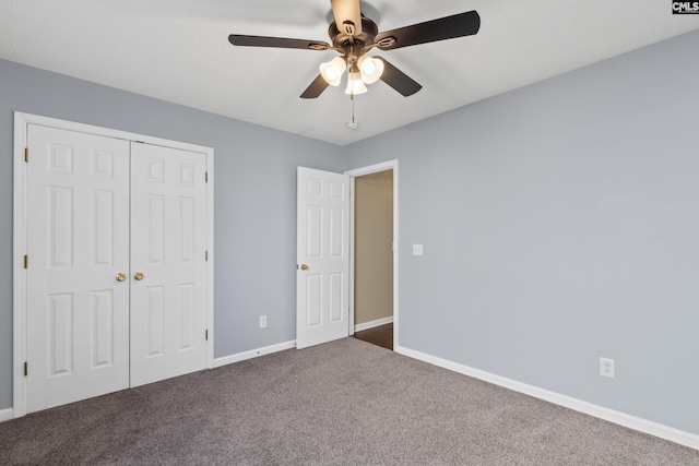 unfurnished bedroom with ceiling fan, dark carpet, and a closet