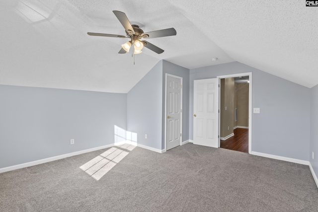 additional living space featuring dark colored carpet, a textured ceiling, vaulted ceiling, and ceiling fan