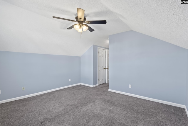 bonus room featuring a textured ceiling, vaulted ceiling, dark carpet, and ceiling fan