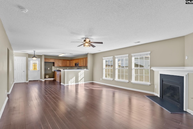 unfurnished living room featuring a textured ceiling, ceiling fan, and dark hardwood / wood-style floors