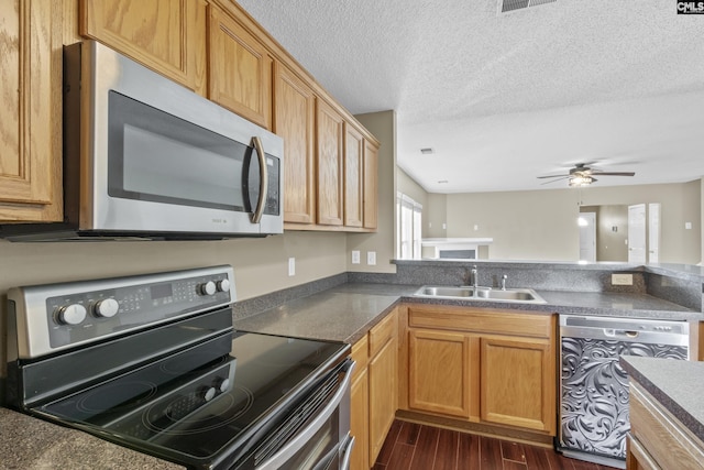 kitchen featuring ceiling fan, sink, kitchen peninsula, a textured ceiling, and appliances with stainless steel finishes