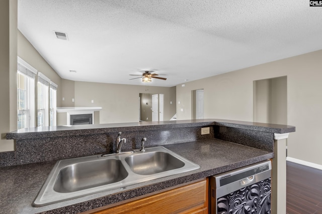 kitchen with dishwashing machine, sink, a textured ceiling, and dark wood-type flooring