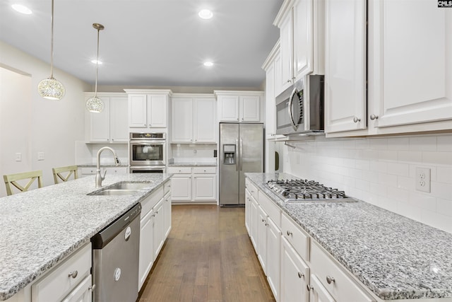 kitchen featuring white cabinets, sink, stainless steel appliances, and a kitchen island with sink