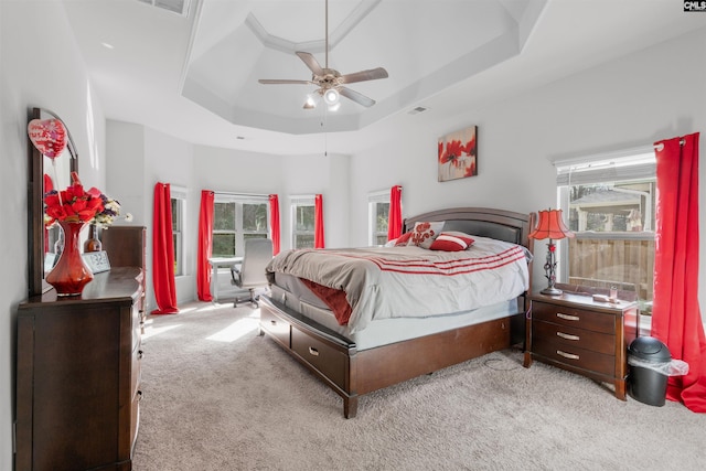 carpeted bedroom featuring a raised ceiling and ceiling fan