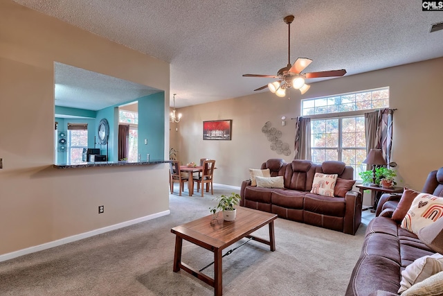 carpeted living room featuring ceiling fan with notable chandelier and a textured ceiling