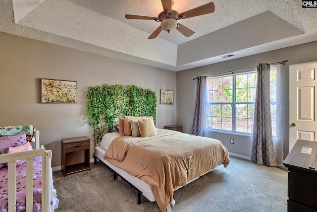 bedroom featuring a textured ceiling, a tray ceiling, ceiling fan, and carpet floors