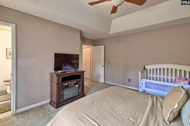 carpeted bedroom featuring ceiling fan, a closet, a textured ceiling, and ensuite bath