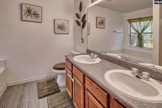 bathroom featuring hardwood / wood-style flooring, vanity, a bath, and toilet