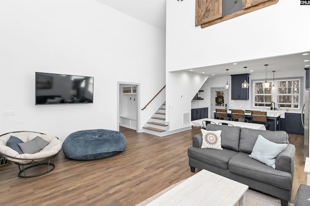 living room featuring sink, dark wood-type flooring, and a high ceiling