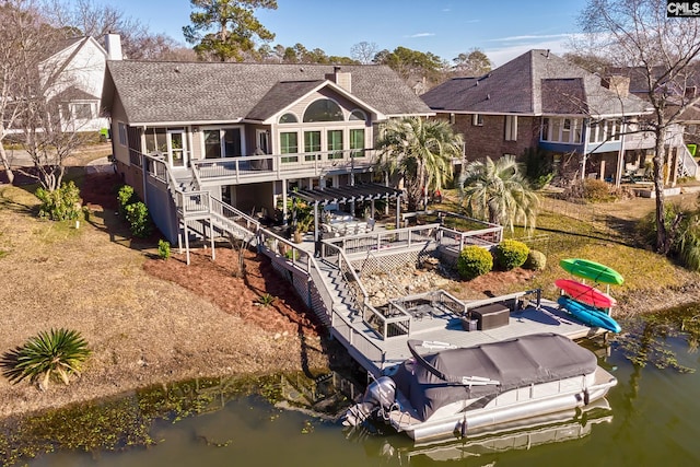 rear view of property featuring a sunroom and a deck with water view