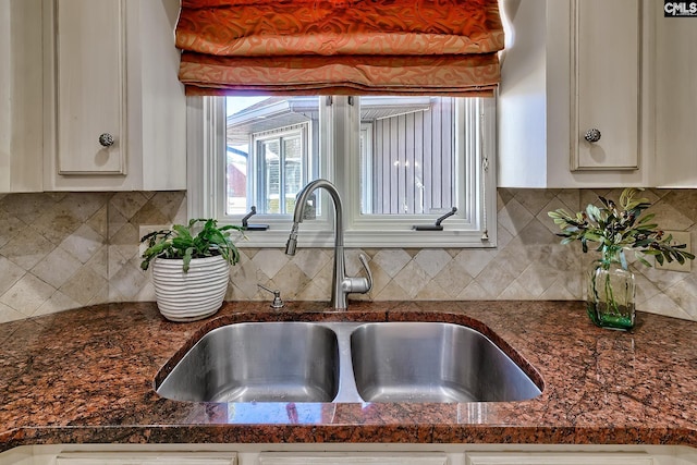 details with backsplash, white cabinets, dark stone countertops, and sink