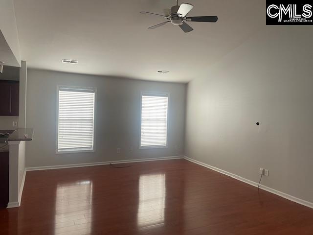 unfurnished living room with dark wood-type flooring, ceiling fan, and a healthy amount of sunlight