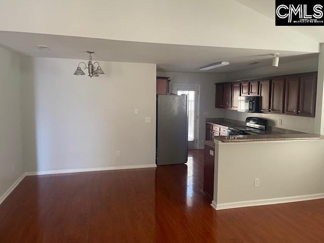 kitchen with dark wood-type flooring, stainless steel refrigerator, stove, dark brown cabinetry, and kitchen peninsula