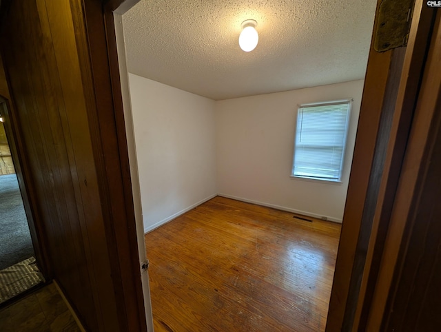 spare room featuring hardwood / wood-style floors and a textured ceiling