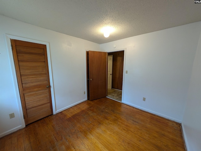 unfurnished bedroom with hardwood / wood-style flooring, a textured ceiling, and a closet