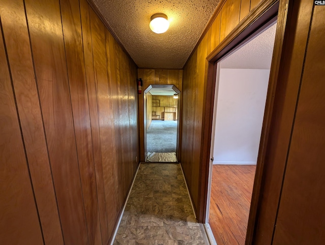 corridor with a textured ceiling and wooden walls