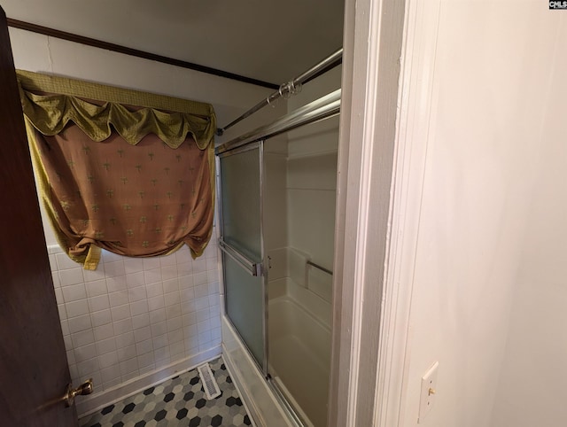 bathroom with tile patterned floors, enclosed tub / shower combo, and tile walls