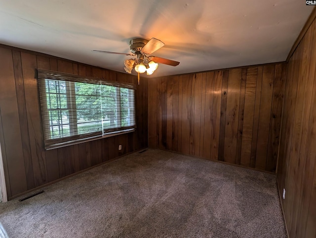 unfurnished room with wood walls, carpet, and ceiling fan