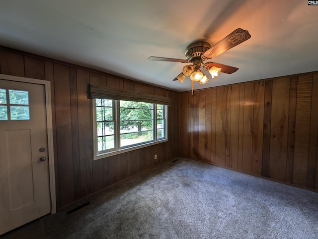 entrance foyer featuring ceiling fan, wooden walls, and carpet floors